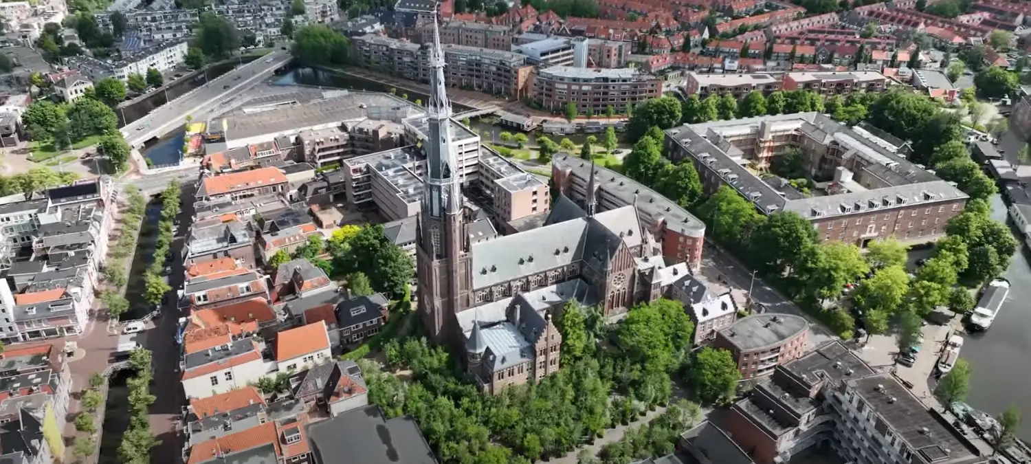 Luchtfoto van een binnenstad met een hoge kerktoren en grachten