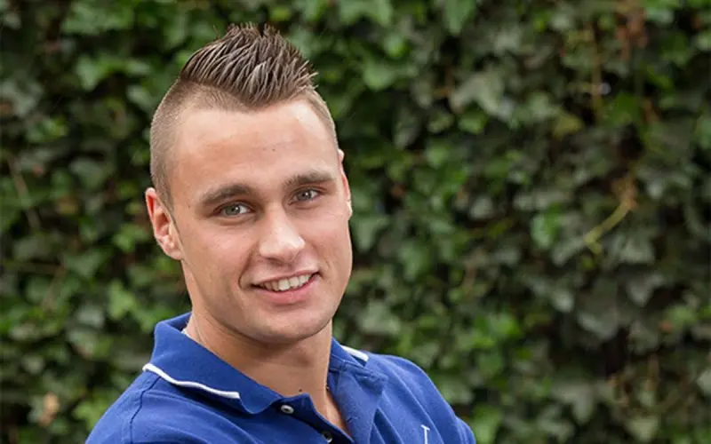 Portret van chauffeur Wim van 't Ende voor een klimopmuur