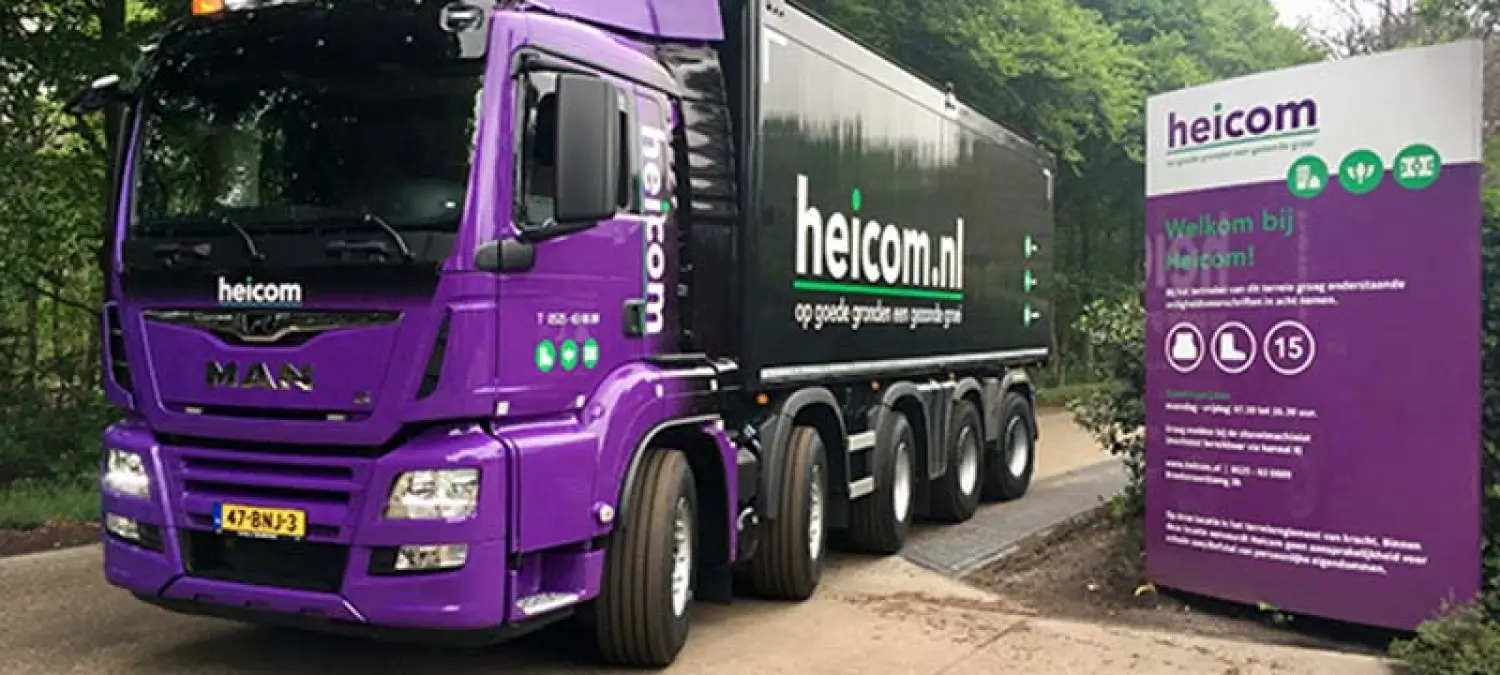 Paarse Heicom-vrachtwagen naast een welkomstbord op het bedrijfsterrein