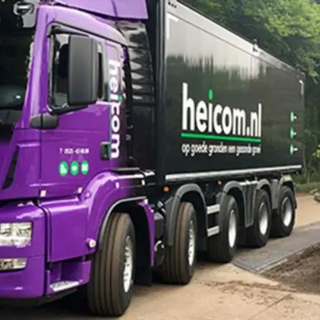 Paarse Heicom-vrachtwagen naast een welkomstbord op het bedrijfsterrein