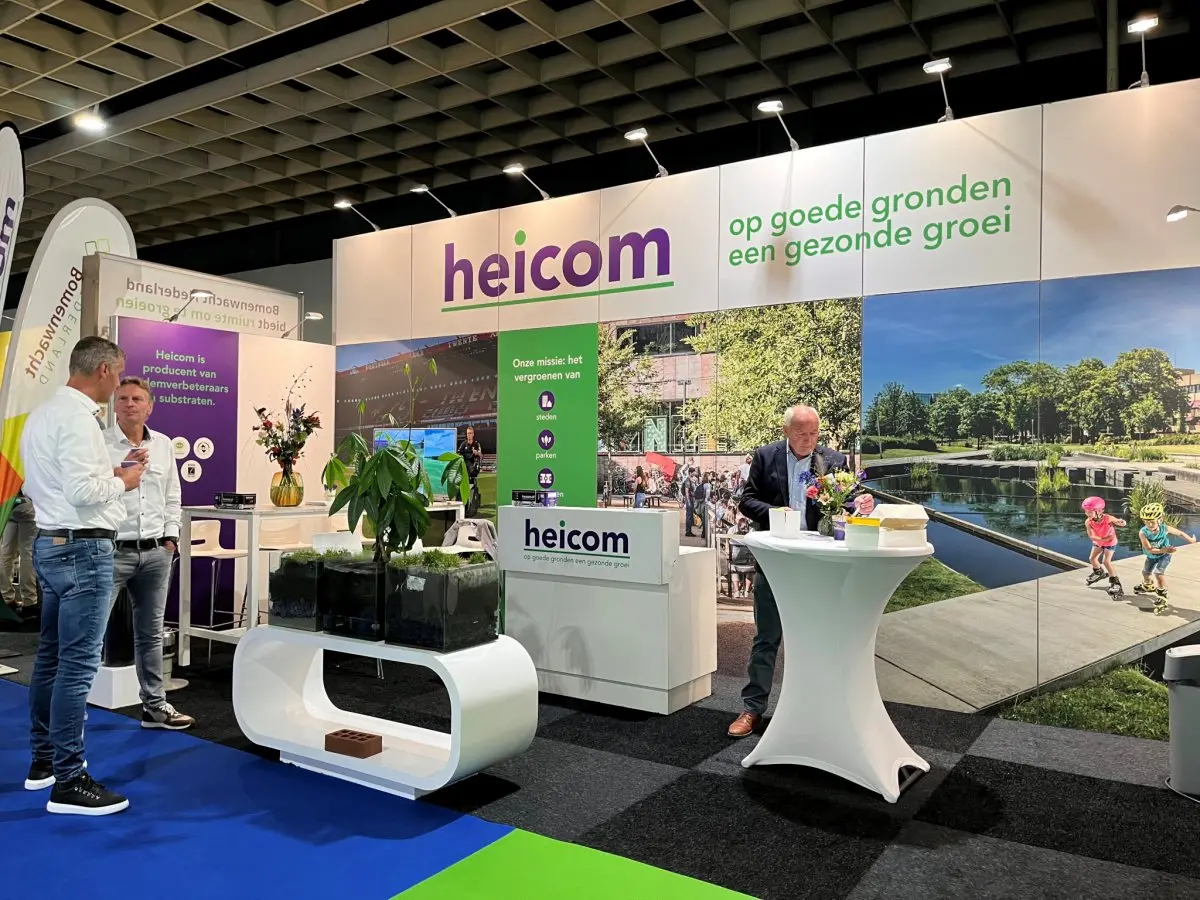 Heicom-beursstand met grote fotowanden en bezoekers in gesprek