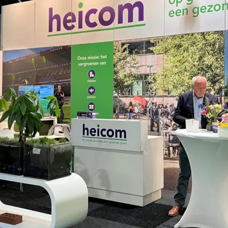 Man aan een statafel en bezoekers in gesprek op een beursstand