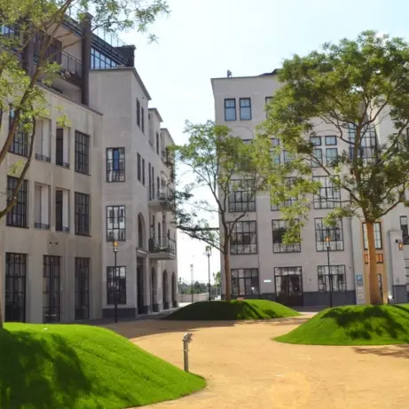 Binnenhof met grasheuvels en jonge bomen tussen appartementengebouwen