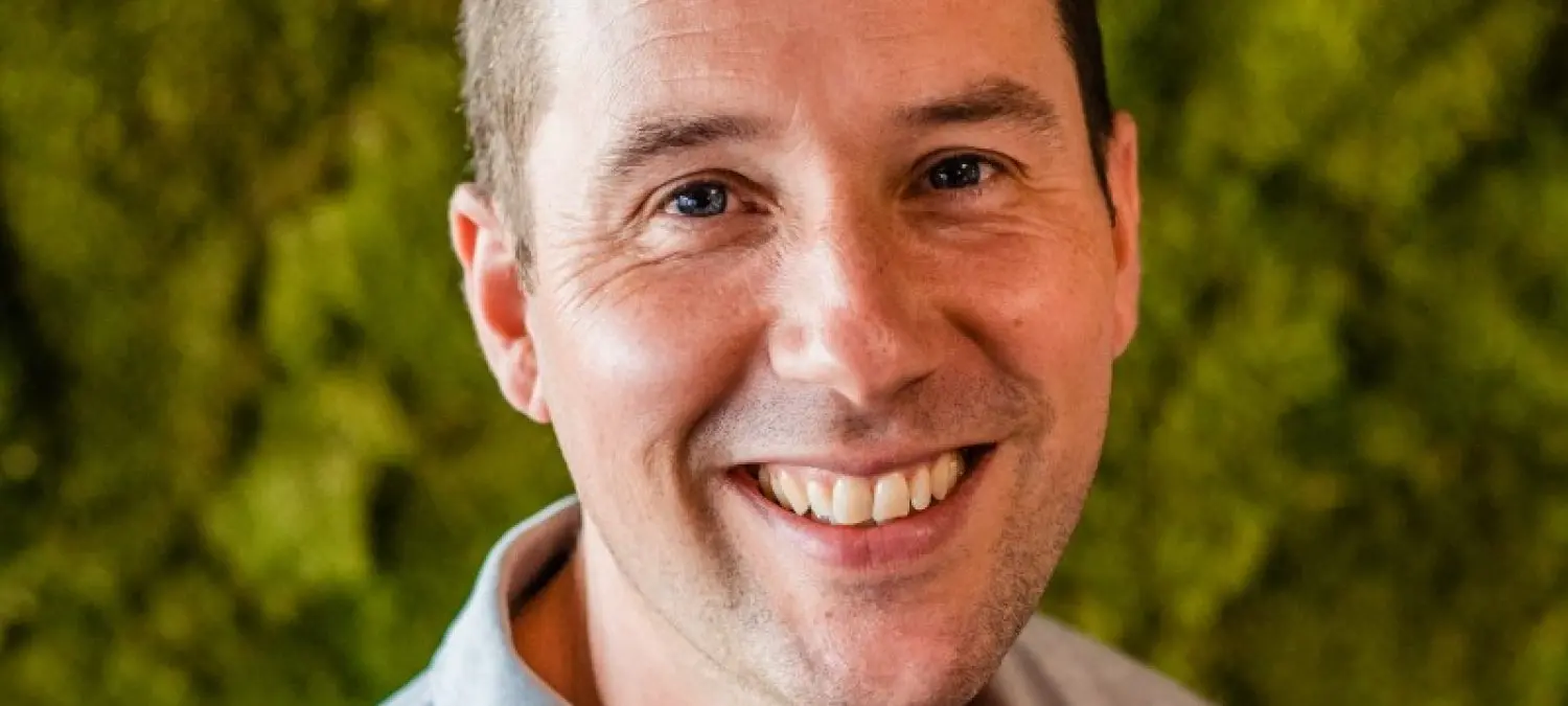 Portret van Joeri Faas lachend voor een groene moswand
