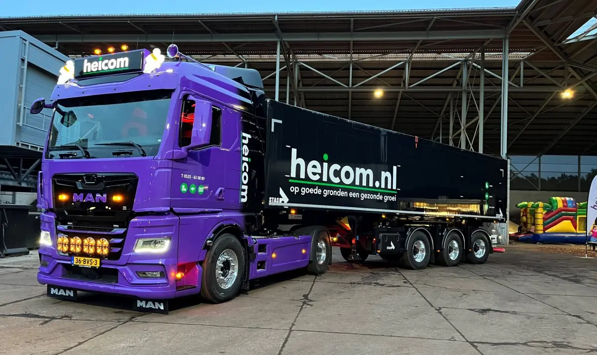 Paarse MAN-vrachtwagen met zwarte kiptrailer met het opschrift heicom.nl