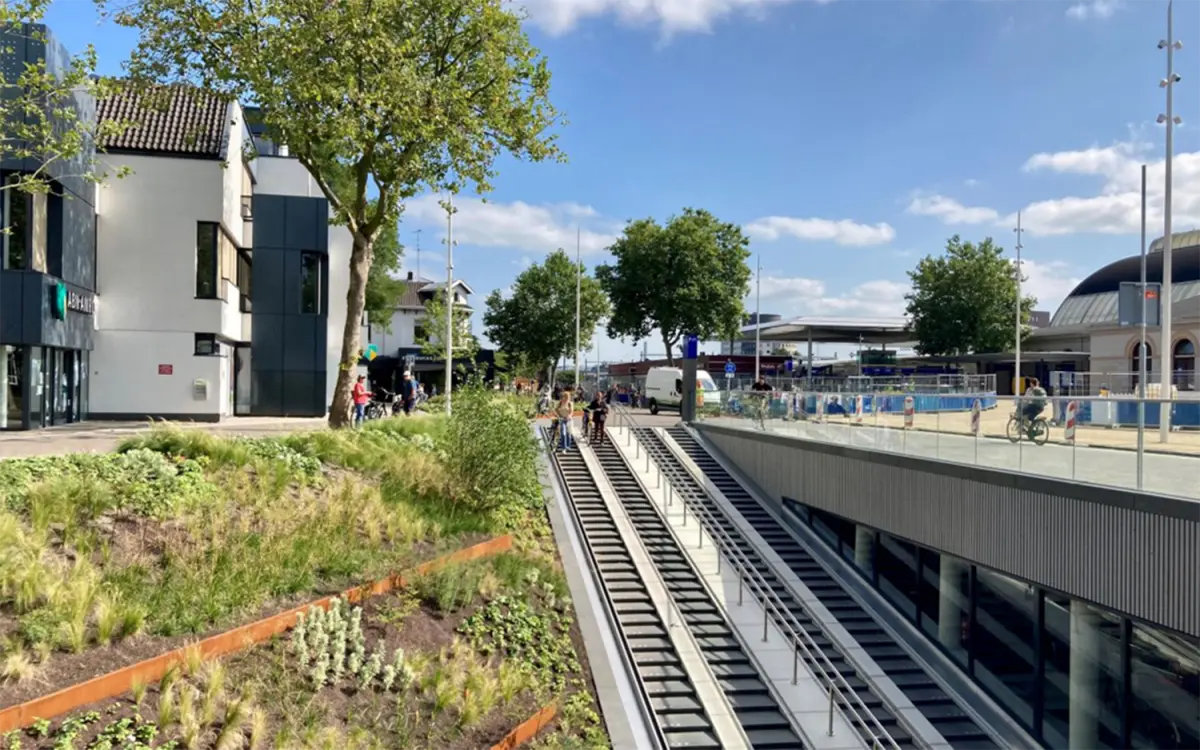Beplantingsvak met siergrassen langs de roltrappen van een fietstunnel bij een station