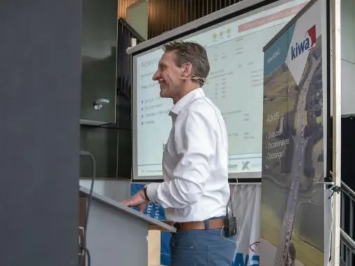 Spreker kijkt naar zijn dia met bodemanalyse op een projectiescherm