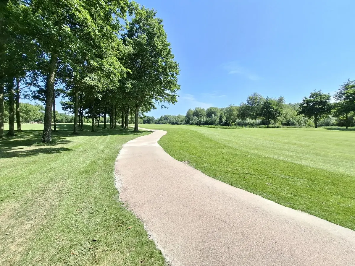 Halfverhard pad slingert door een golfbaan met gras en bomen