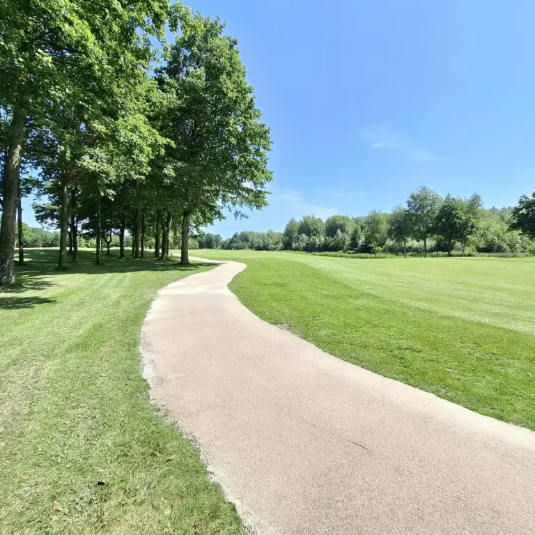 Halfverhard pad slingert door een golfbaan met gras en bomen