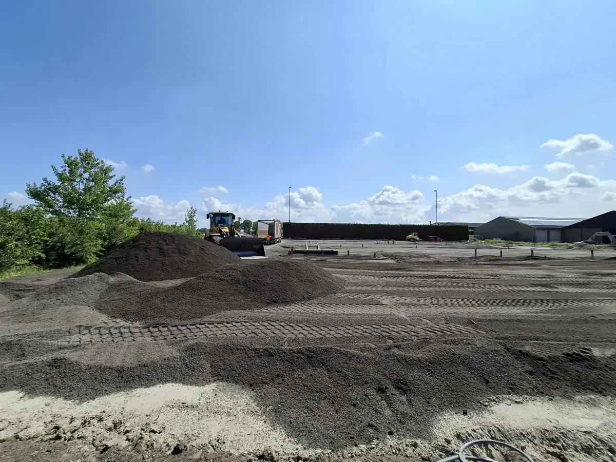 Shovel verdeelt hopen donkere grond op een nieuw parkeerterrein