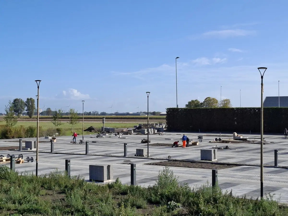 Groot parkeerterrein in aanleg met grasbetontegels en nieuwe lantaarnpalen
