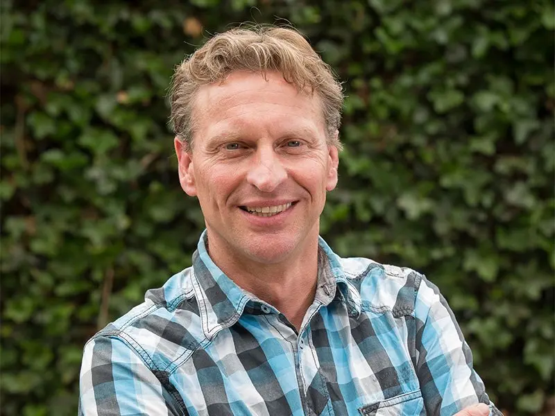 Portret van Marcel Straatman met de armen over elkaar, lachend