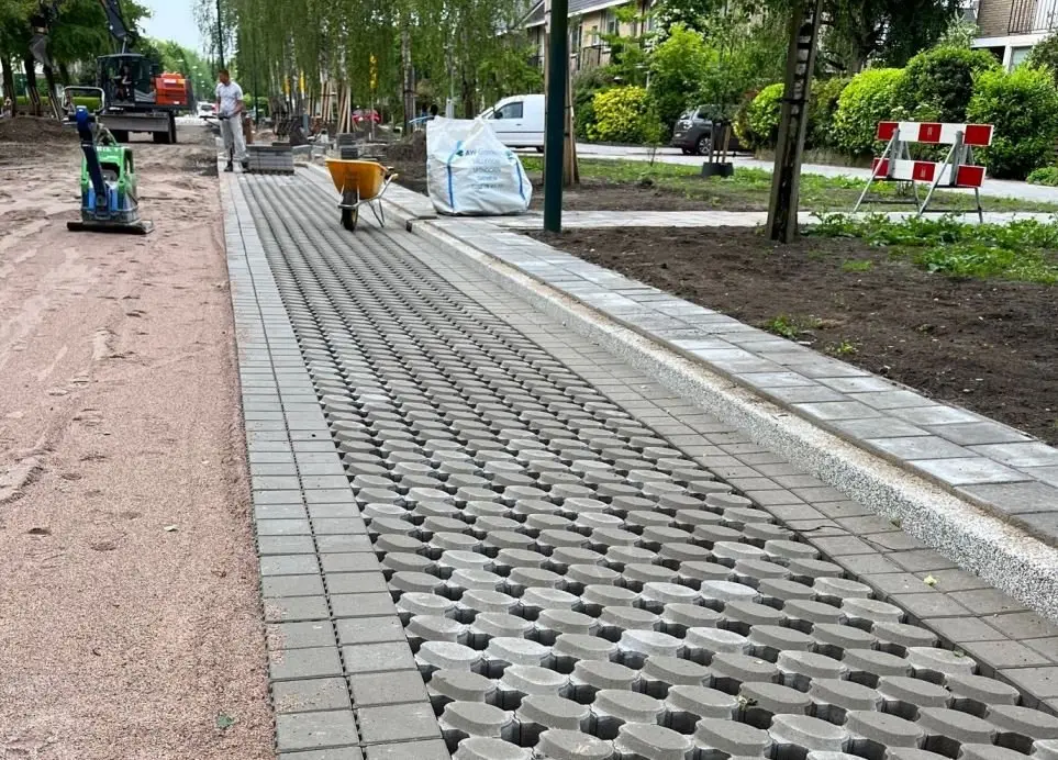Pas gelegde grasbetontegels langs een straat in aanleg met kruiwagen