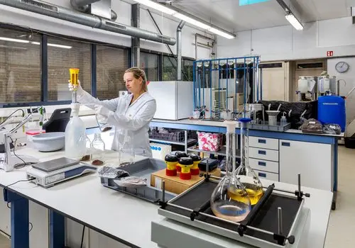 Laborante in witte jas werkt met glaswerk in een laboratorium