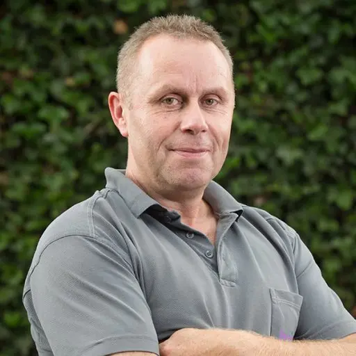 Portret van Erik van Oene met gekruiste armen voor klimop
