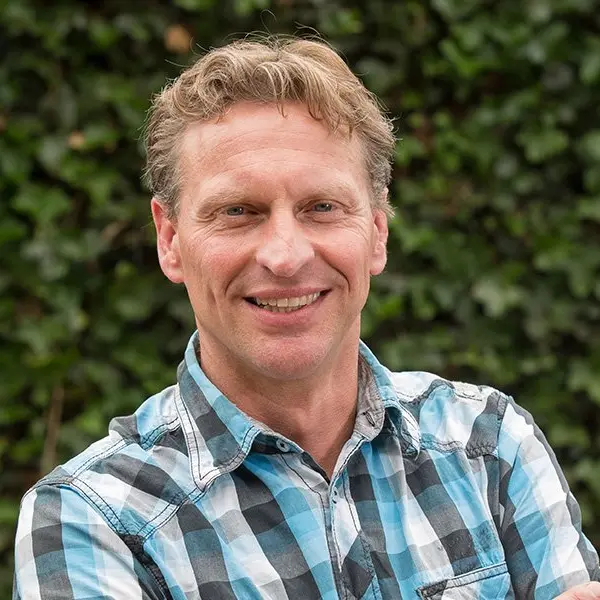 Portret van Marcel Straatman met de armen over elkaar, lachend