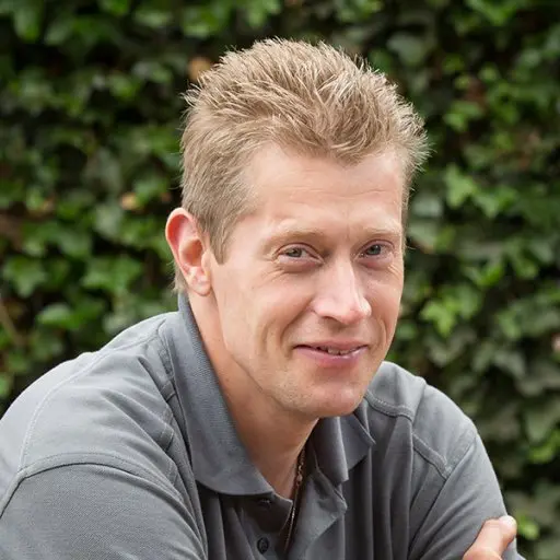 Portret van Rik van der Vegte lachend voor een klimopmuur