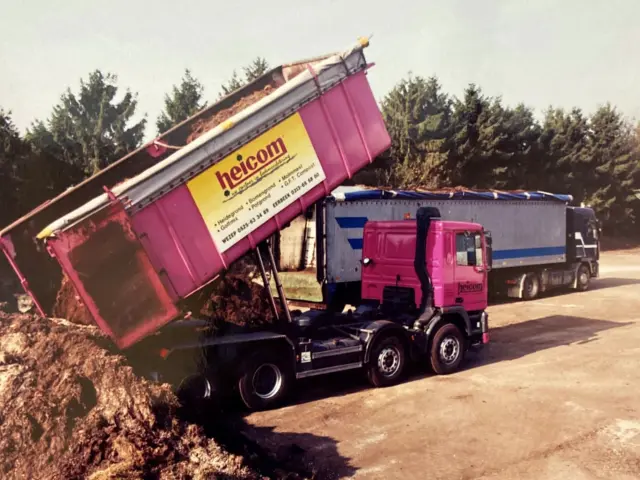 Oude foto van een roze Heicom-vrachtwagen die grond kiept