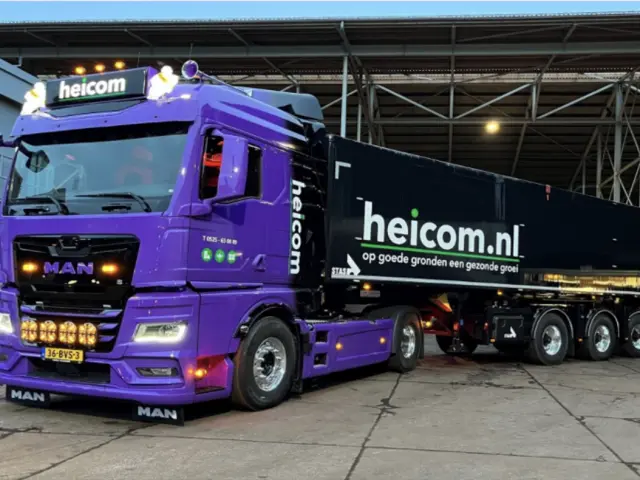 Paarse Heicom-vrachtwagen met zwarte kiepoplegger in een loods
