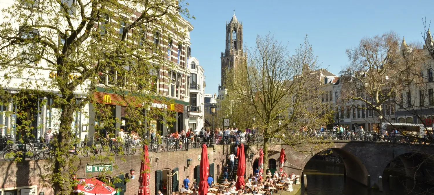Werfterrassen met rode parasols langs de gracht onder de Domtoren