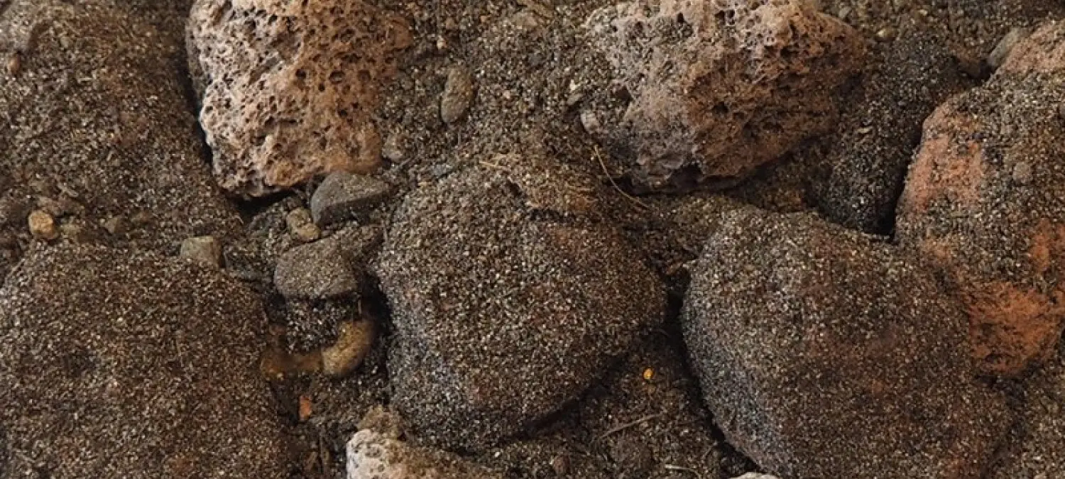 Close-up van grove lava- en basaltbrokken met zand ertussen