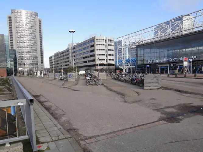 Kaal stationsplein met fietsenstalling en kantoortorens bij Amsterdam Sloterdijk