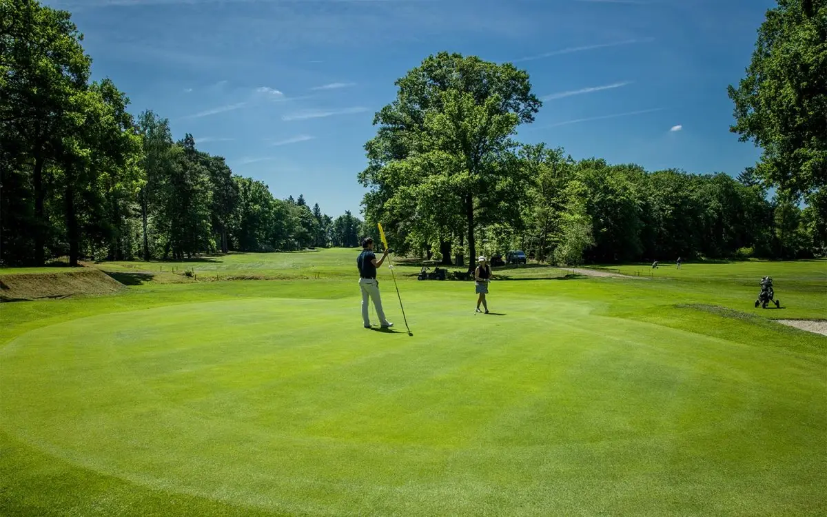 Golfer houdt de vlag vast op een green tussen bomen