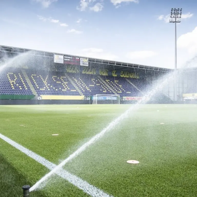 Sproeiers bevochtigen een voetbalveld voor lege tribunes