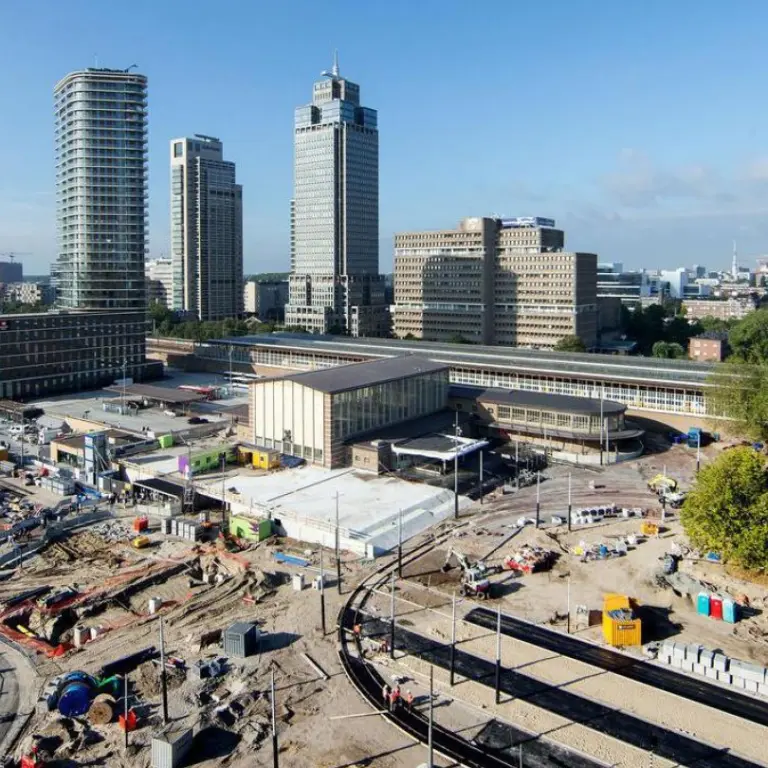 Groot bouwterrein voor een stationsgebouw met hoogbouw op de achtergrond