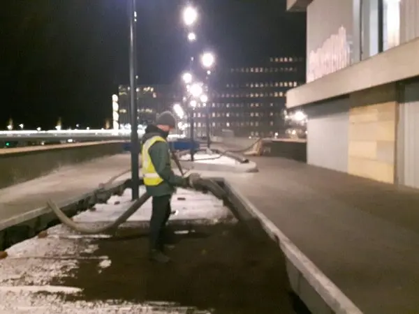 Werkman blaast 's nachts substraat door een slang in een plantvak