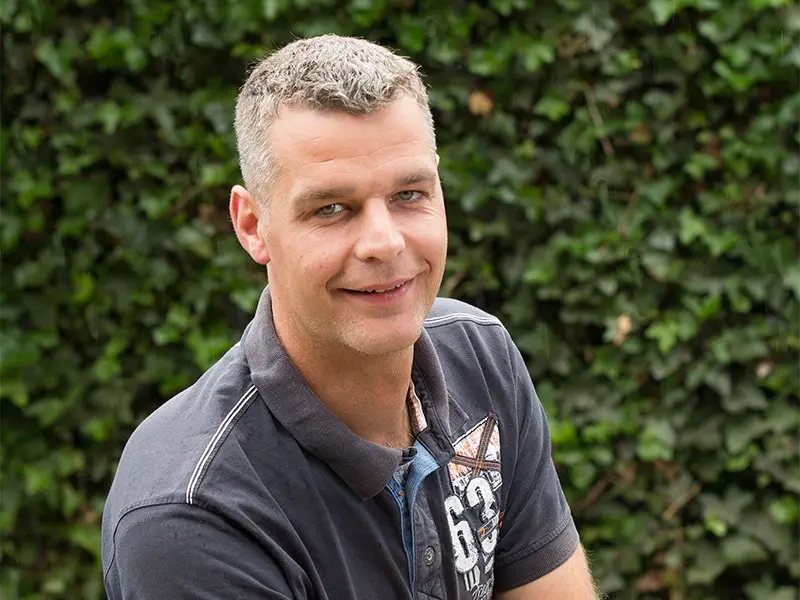 Portret van Herbert van Werven in donkere polo voor een klimopmuur