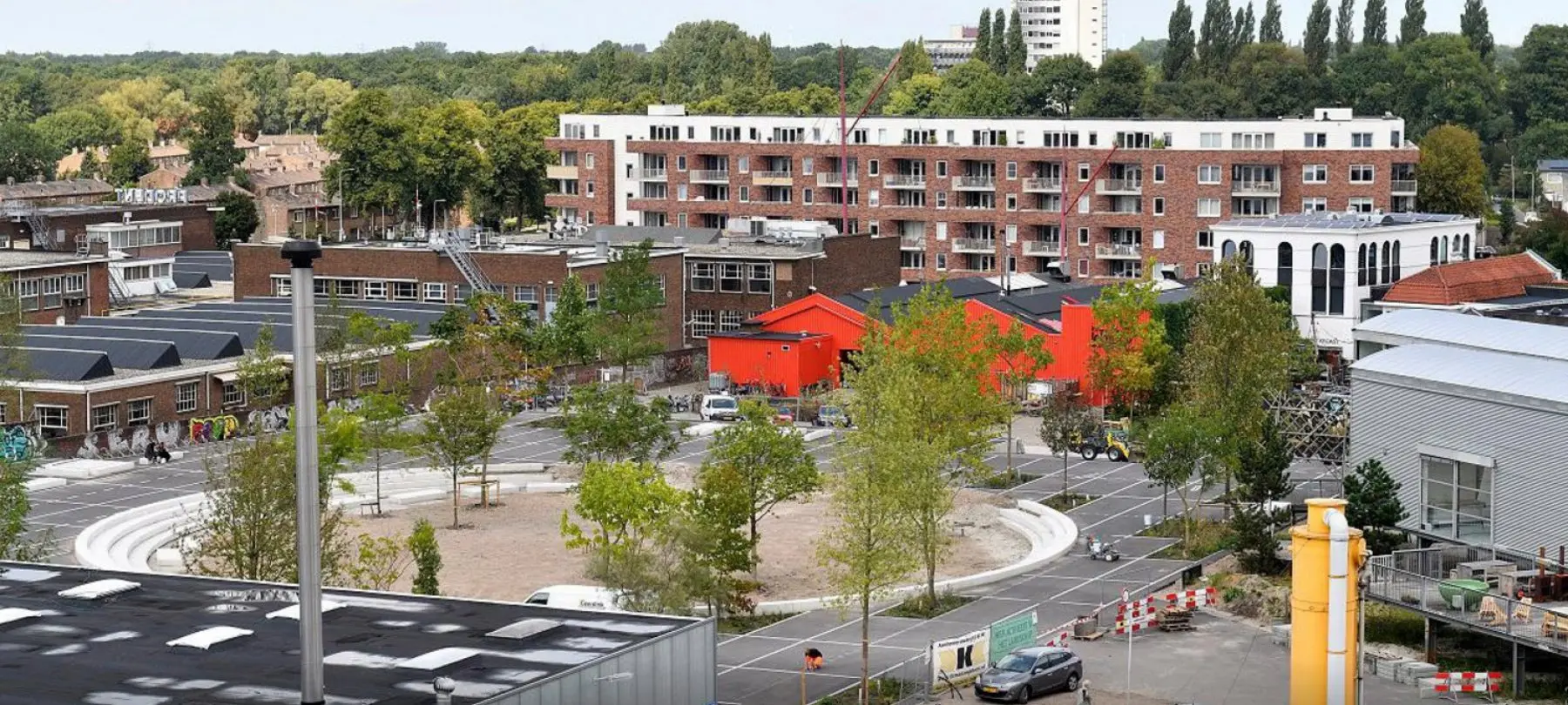 Overzicht van een nieuw aangelegd plein met jonge bomen tussen woonblokken
