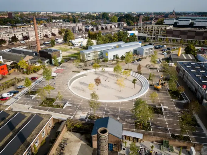 Luchtfoto van een rond plein met trappen, bomen en parkeervakken