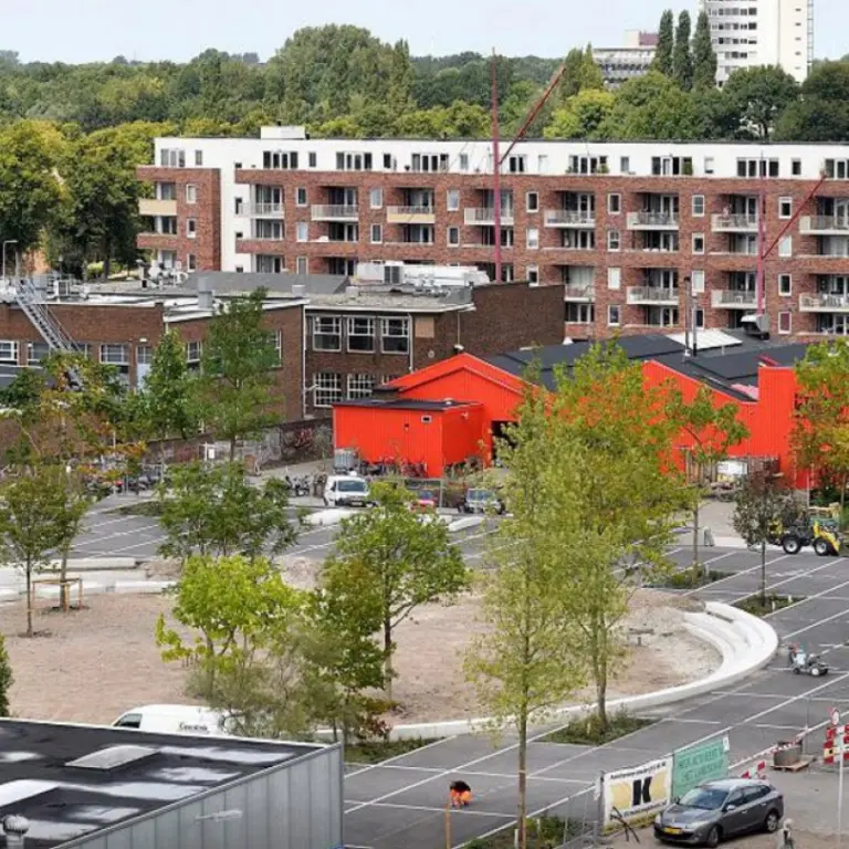 Overzicht van een nieuw aangelegd plein met jonge bomen tussen woonblokken