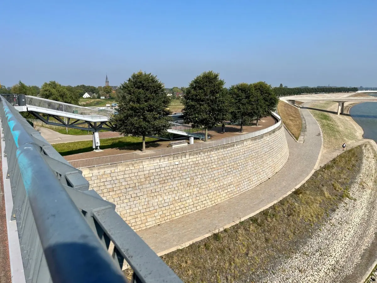 Uitzicht vanaf een brug op een gebogen kademuur met bomen erop