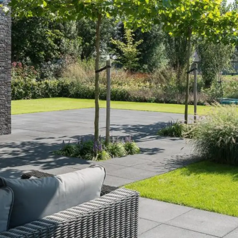 Loungebank op een terras met gazon en siergrassen in een tuin