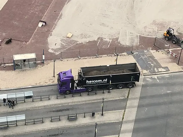 Heicom-vrachtwagen met beladen kipper langs de weg, van bovenaf gezien