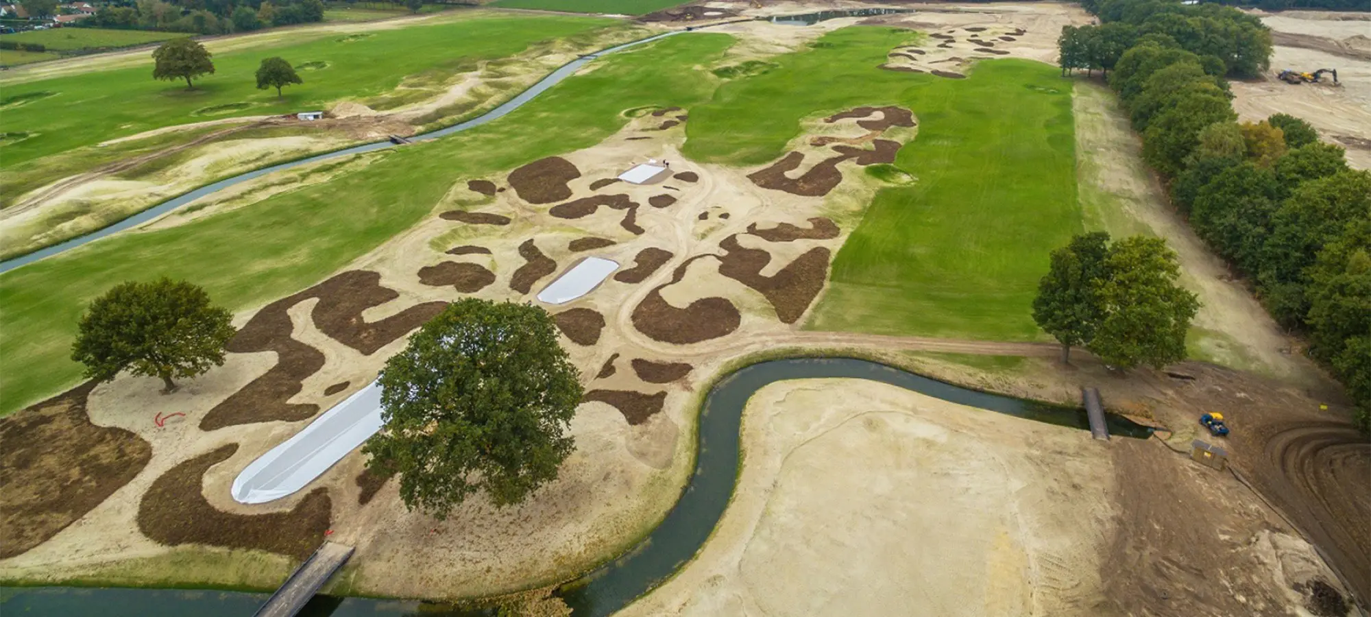 Luchtfoto van een golfbaan in aanleg met bunkers en grondwerk