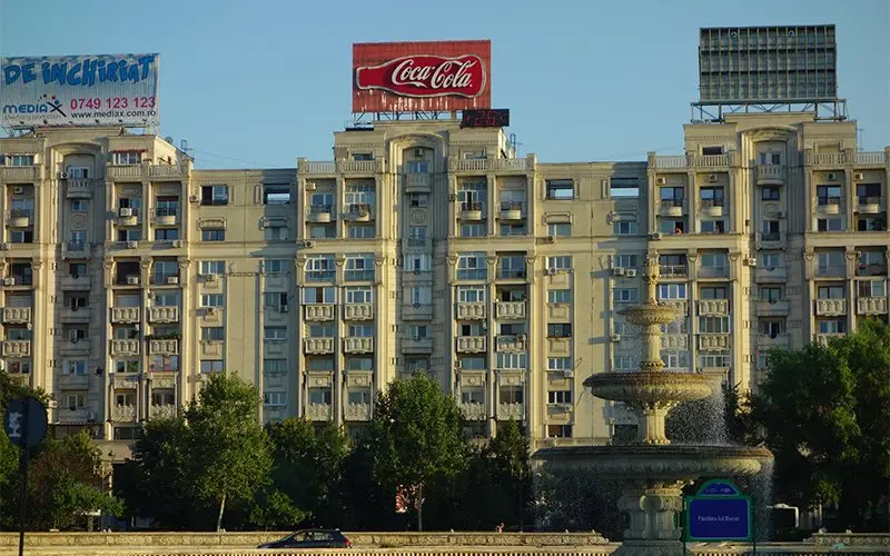 Fontein voor een groot flatgebouw met reclameborden op het dak
