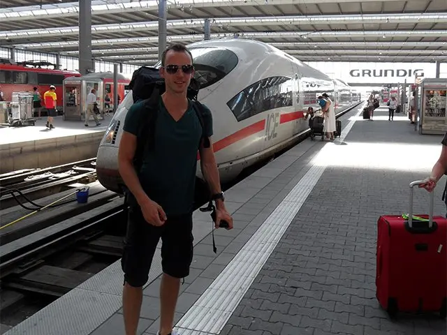 Man met rugzak op een perron voor een witte hogesnelheidstrein