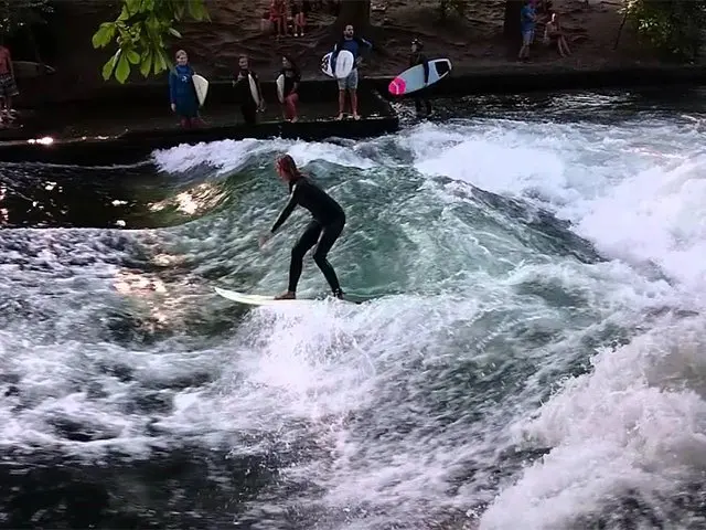 Surfer op een staande golf in een stadsrivier met toeschouwers