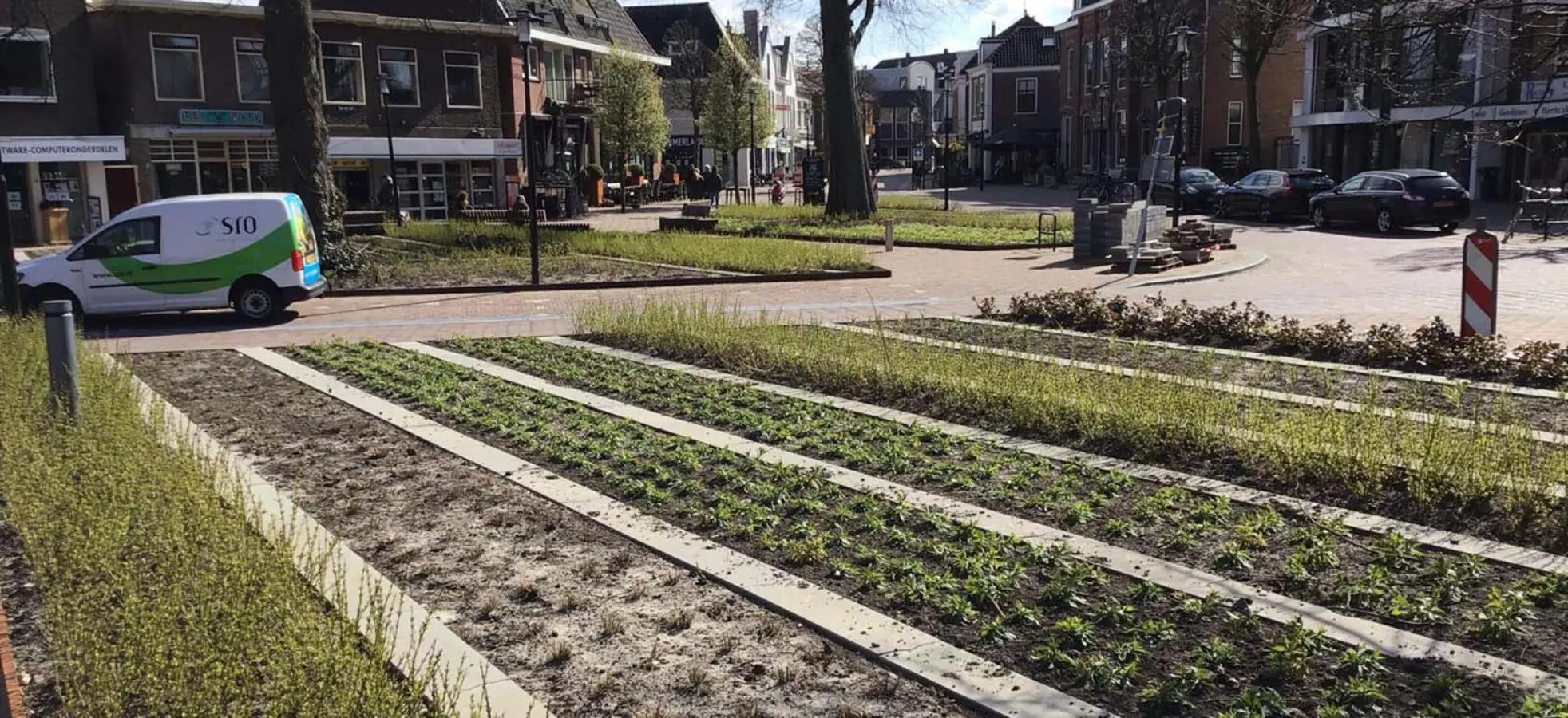 Nieuw plein met stroken jonge beplanting tussen betonnen randen