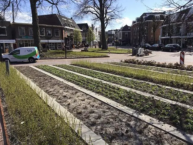Pas ingeplante borders met betonstroken op een dorpsplein met winkels