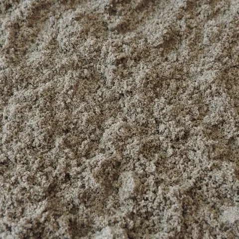 Opgehoopt zand met bruine en lichtgrijze korrels van dichtbij