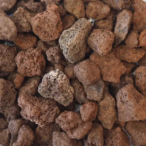 Brokken roodbruine lavasteen met poreuze gaatjes op een hoop