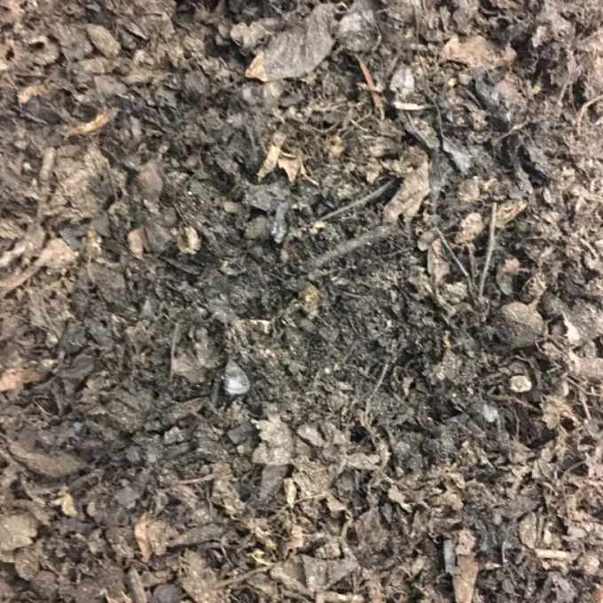 Grove bruingrijze mulch met bladresten en takjes van dichtbij