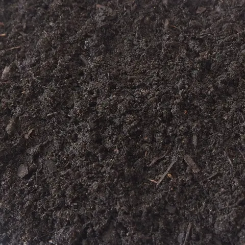 Donkerbruine compost met lichte houtvezels en kluitjes ertussen