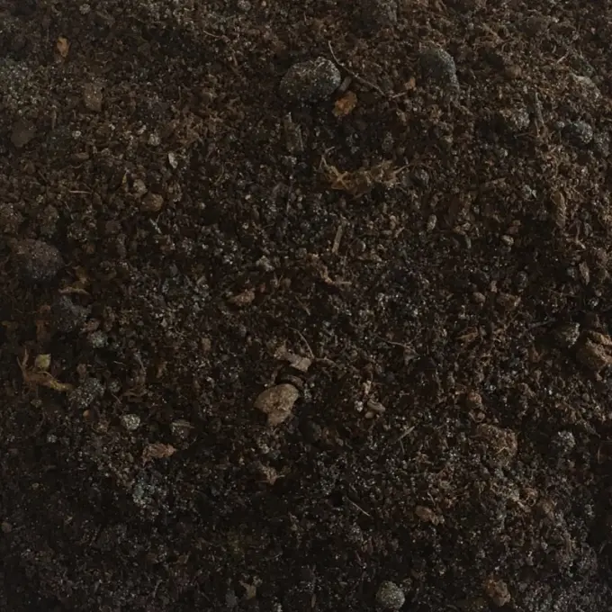 Donkerbruine grond met vezelige plantenresten en kleine kluitjes