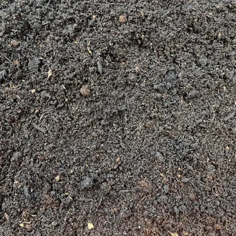 Zwarte kruimelige compost met lichte vezels ertussen