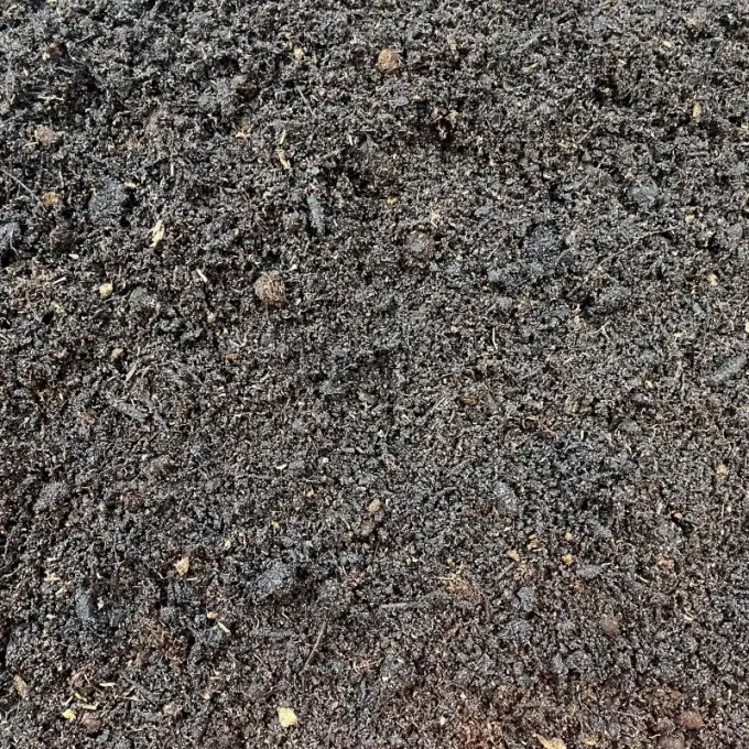 Zwarte kruimelige compost met lichte vezels ertussen
